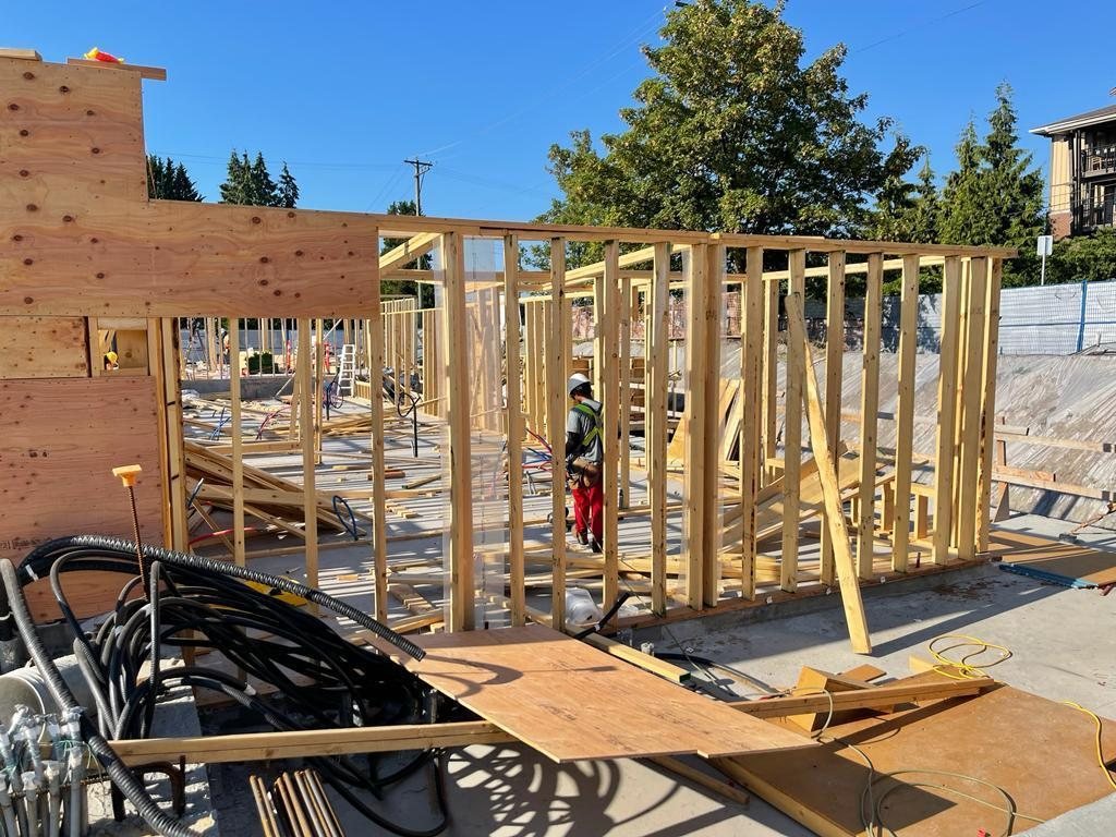 Exterior wood wall framing with partial sheathing and diagonal temporary braces on a concrete floor.