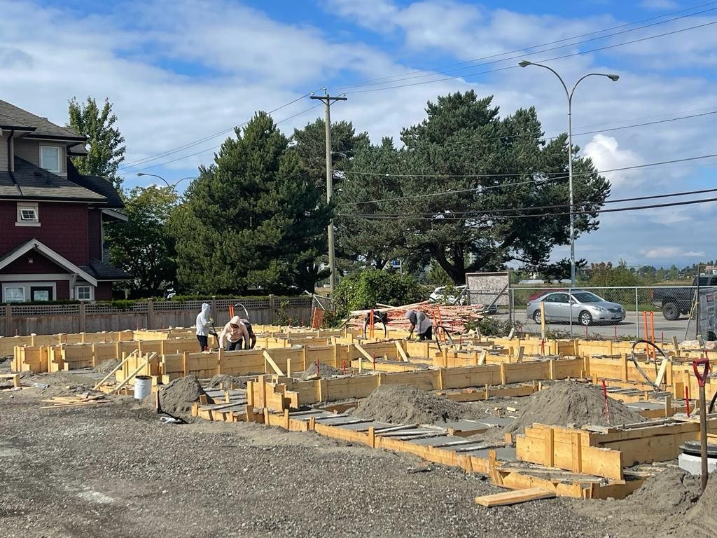 Timber foundation forms arranged across a compact site beside an existing home and overhead utility lines.