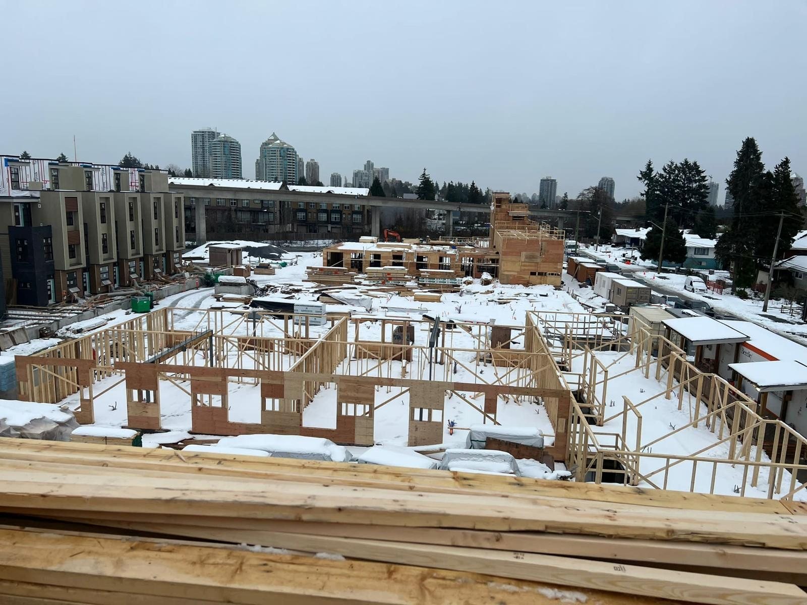 Wood framing materials and partial wall construction under snow at a multi-building site.