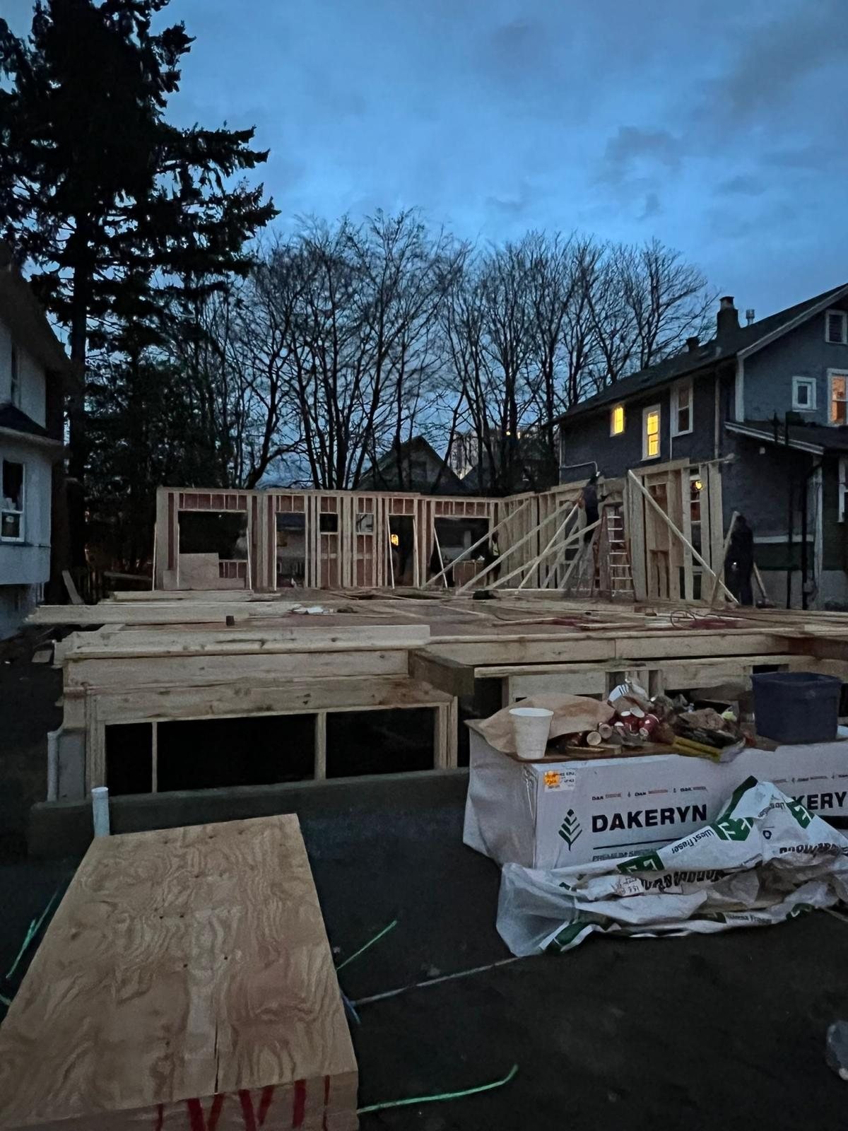 Partially framed low-rise building with plywood and materials on the ground.