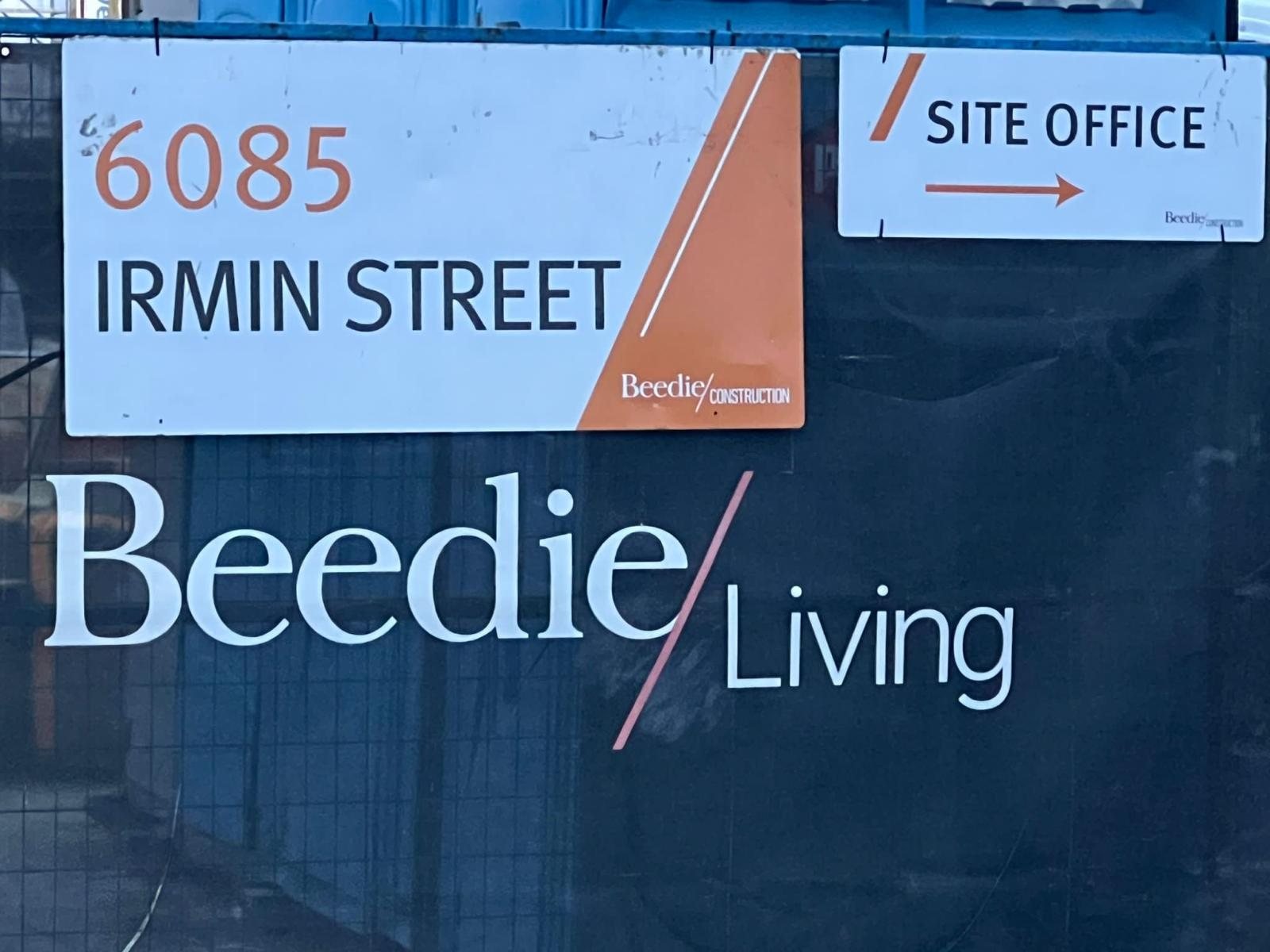 Temporary construction fence with a site-office direction sign and project branding.