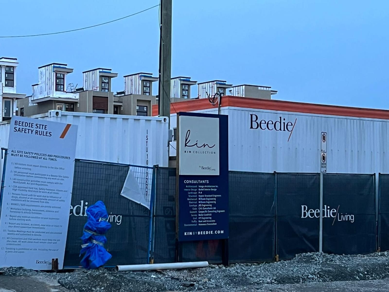 Construction entrance with a project sign, fencing and stored materials.