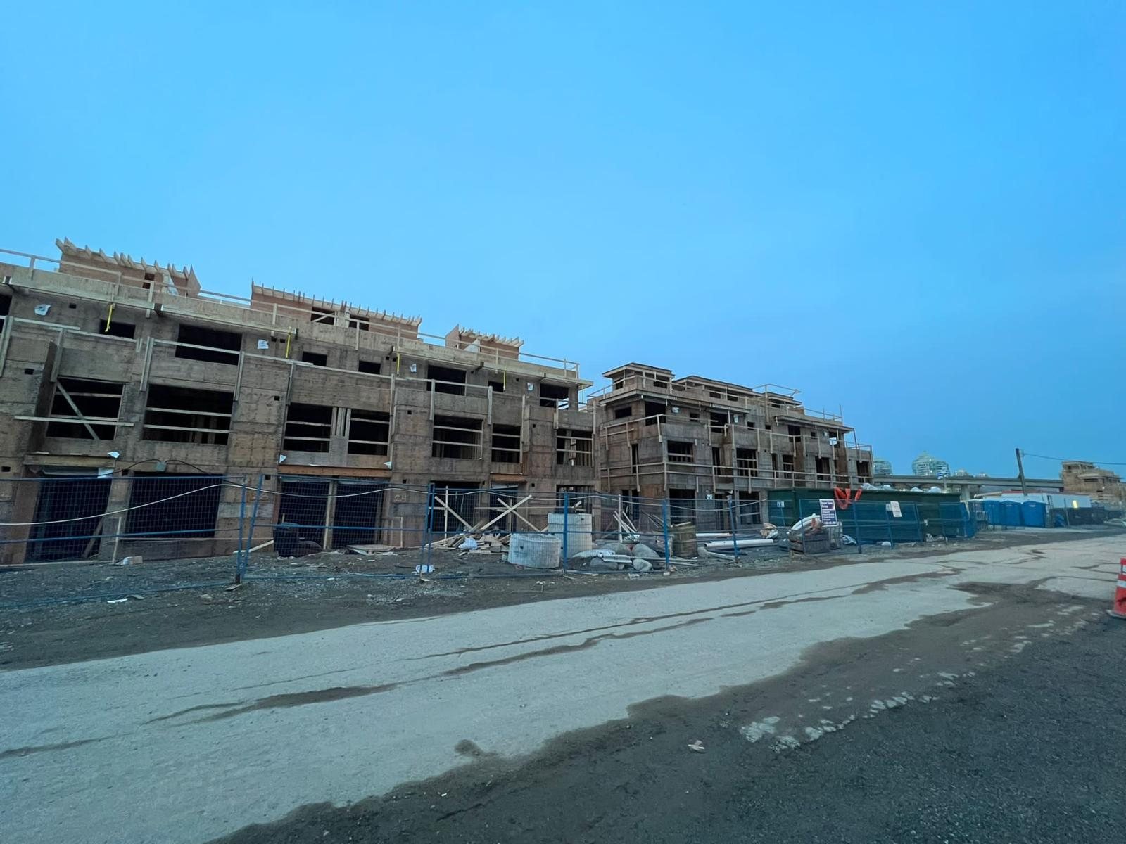 Long row of multi-unit wood framing viewed from the street on a clear day.