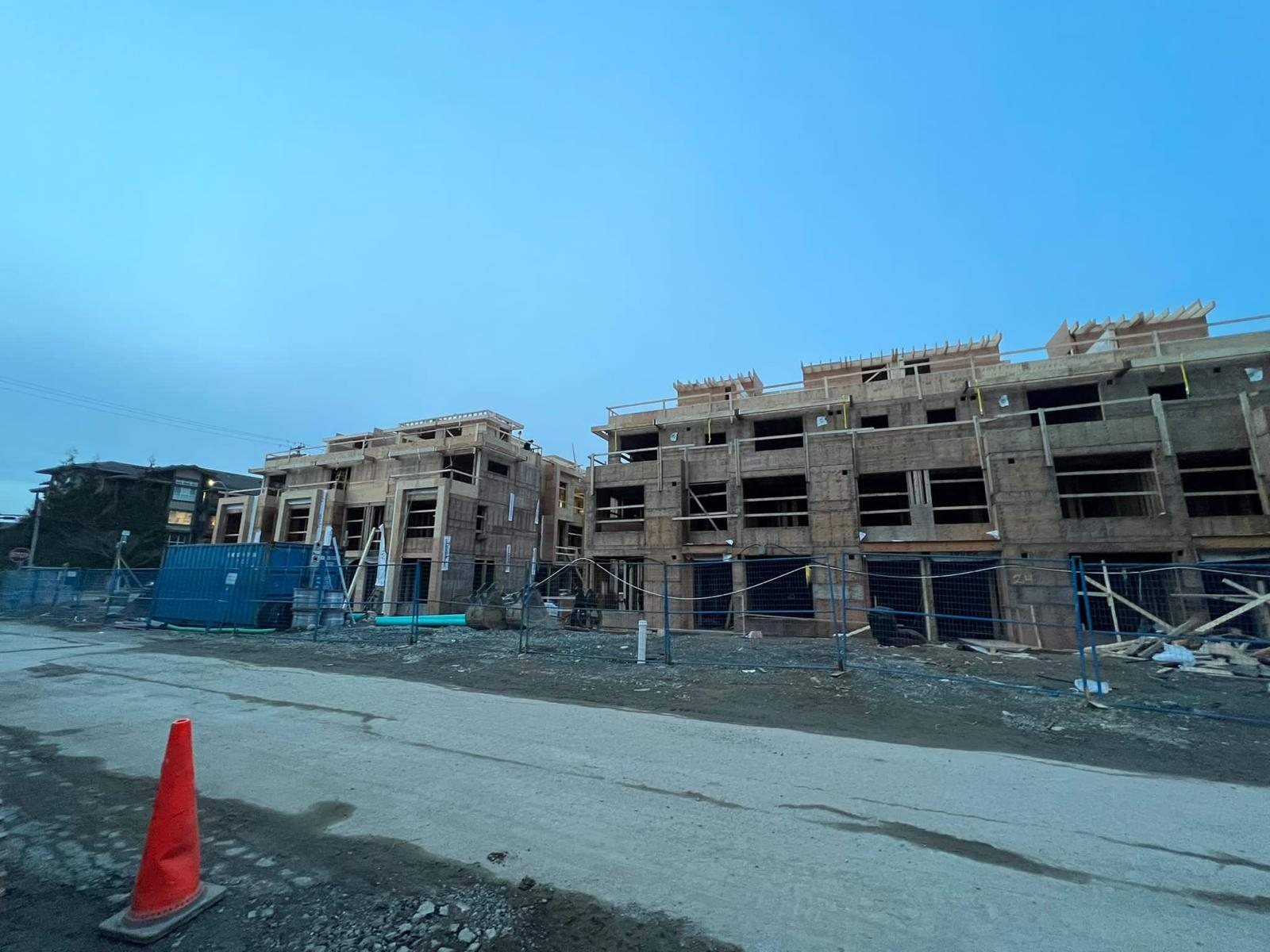 Multi-storey wood framing and site fencing viewed from an open construction lane.
