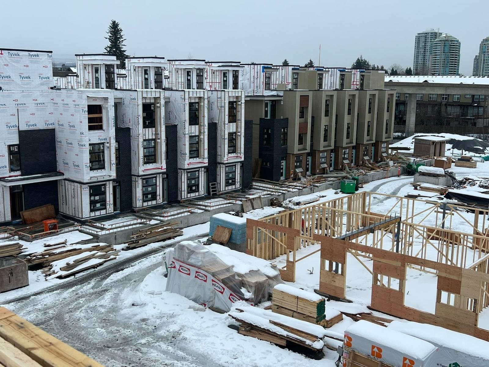 Snow-covered multi-family building frames and materials viewed from above.