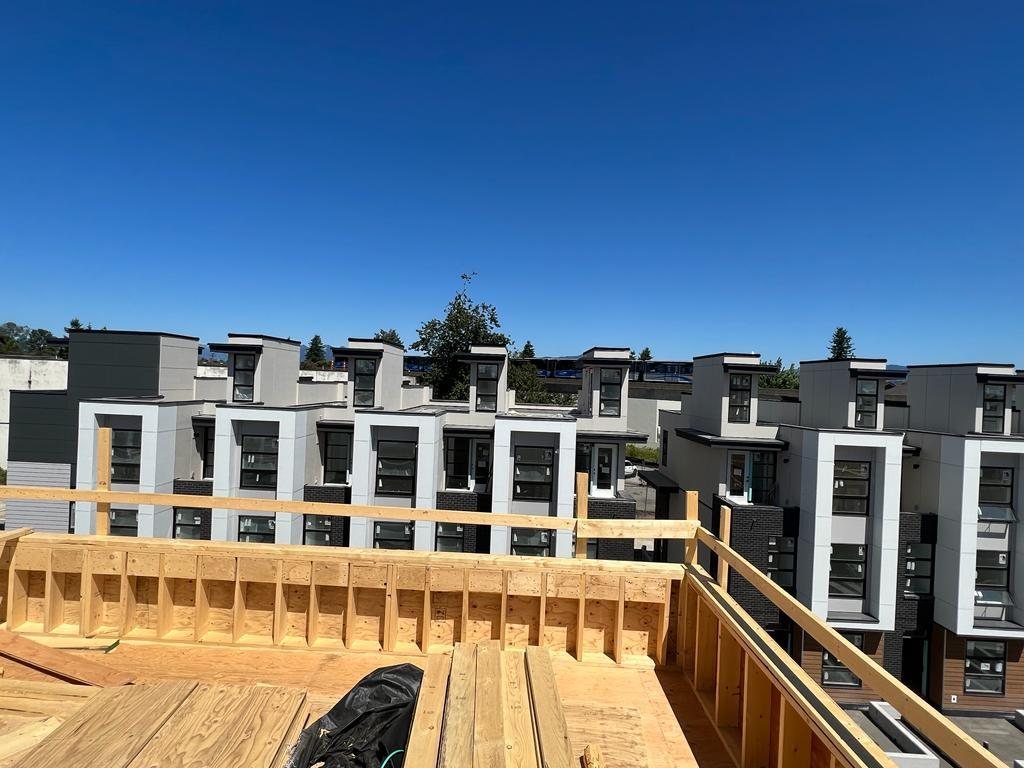 Wood-framed deck edge overlooking a row of completed multi-unit homes.