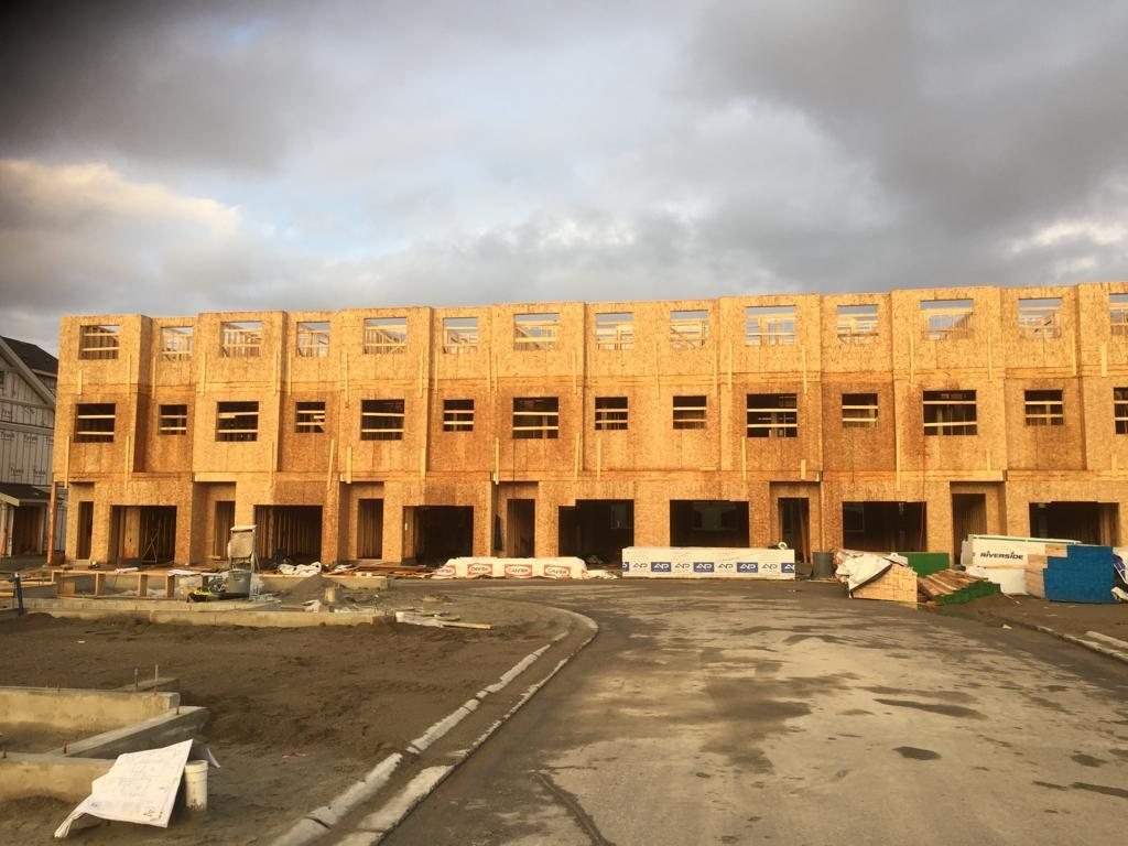 Long wood-framed building covered in structural panels beneath overcast skies.