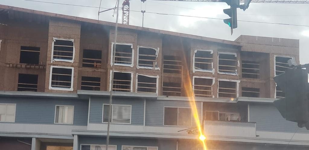 Multi-storey wood-frame exterior with window openings and partial weather protection.