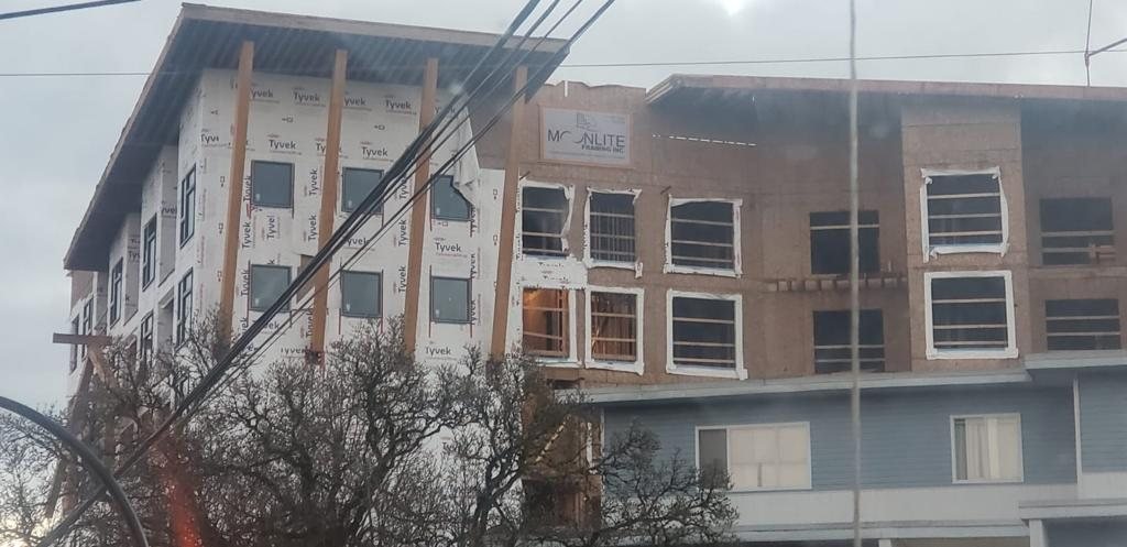 Street-side view of wood framing and window openings on a multi-storey building.