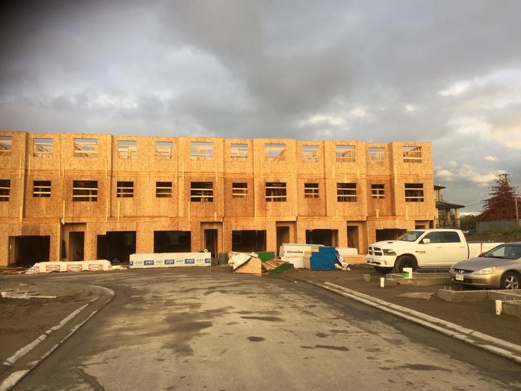 Wide view of a long wood-framed building with open ground-level bays.