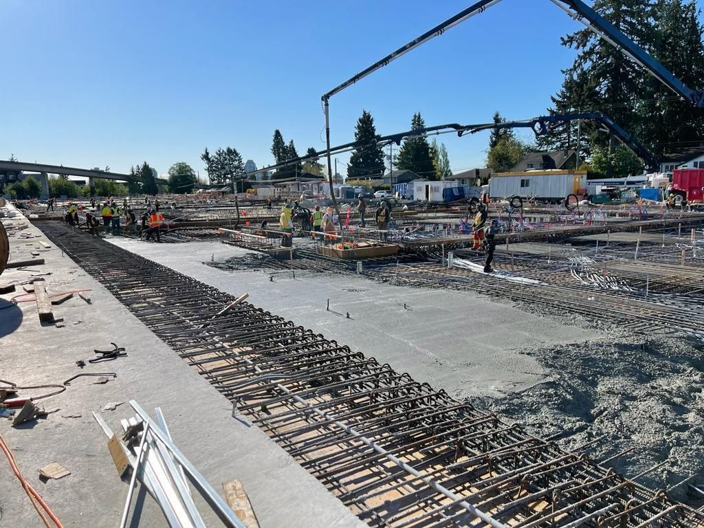Reinforcing steel and service conduits laid across a slab beside its edge.