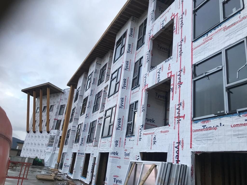Multi-storey exterior wall with weather-resistive wrap around window openings.