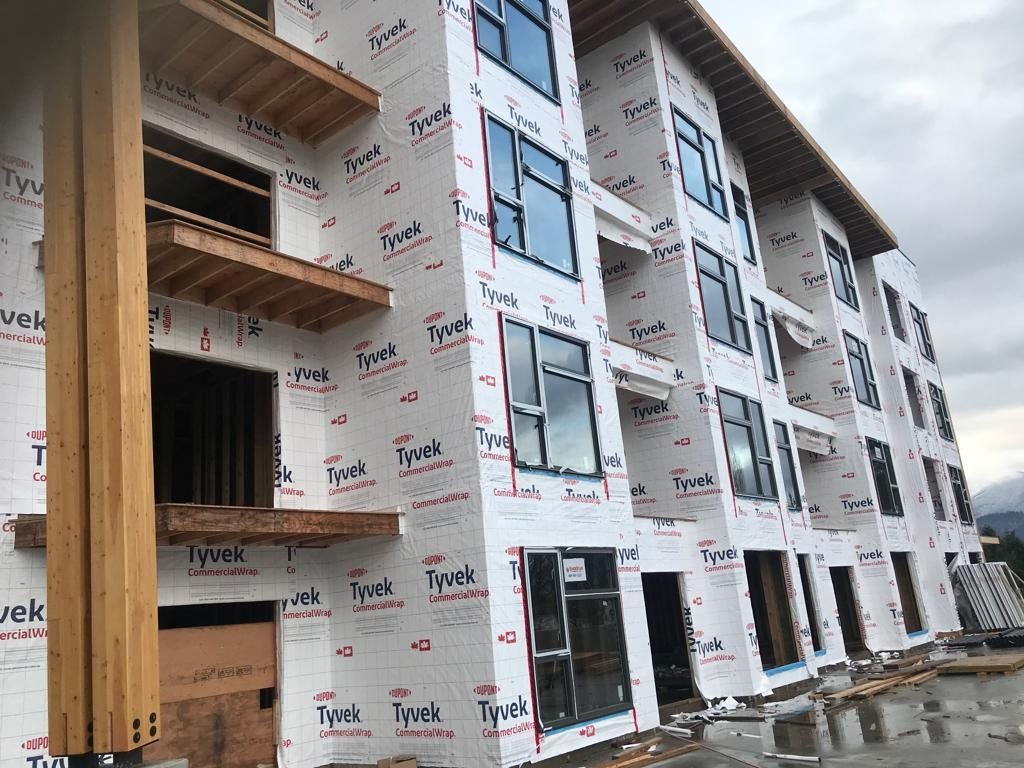 Close view of a projecting wood balcony beside a wrapped multi-storey exterior wall.
