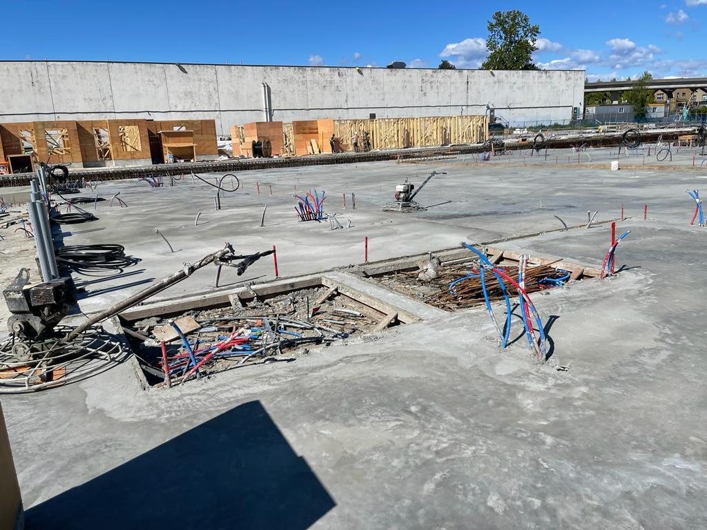 Construction equipment beside an active concrete work area and framed wall sections.