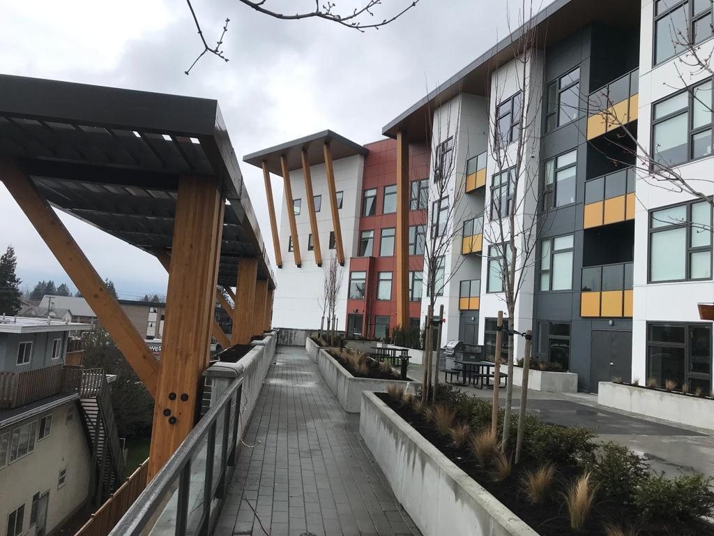 View along a covered walkway with timber supports and multi-storey homes.