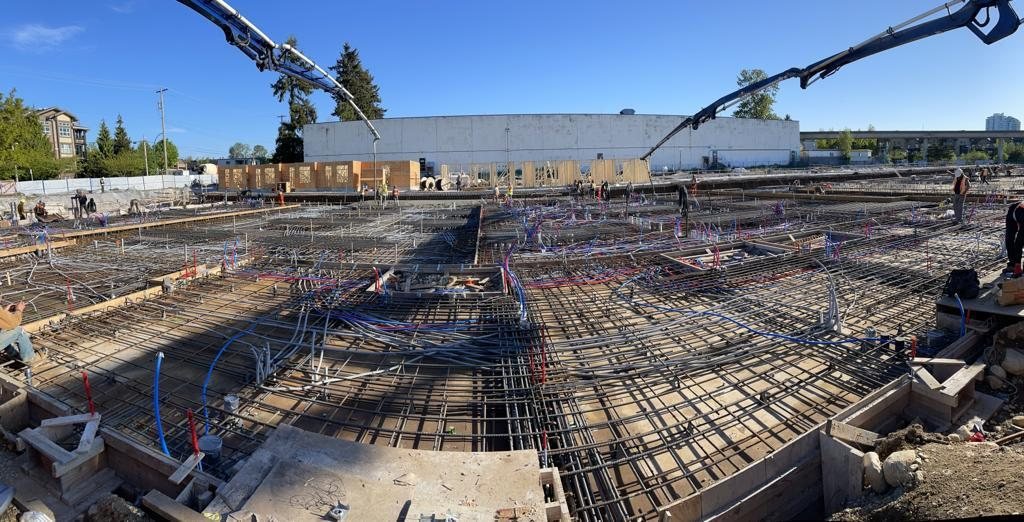 Concrete pump boom over reinforcing steel and service conduits on a slab.