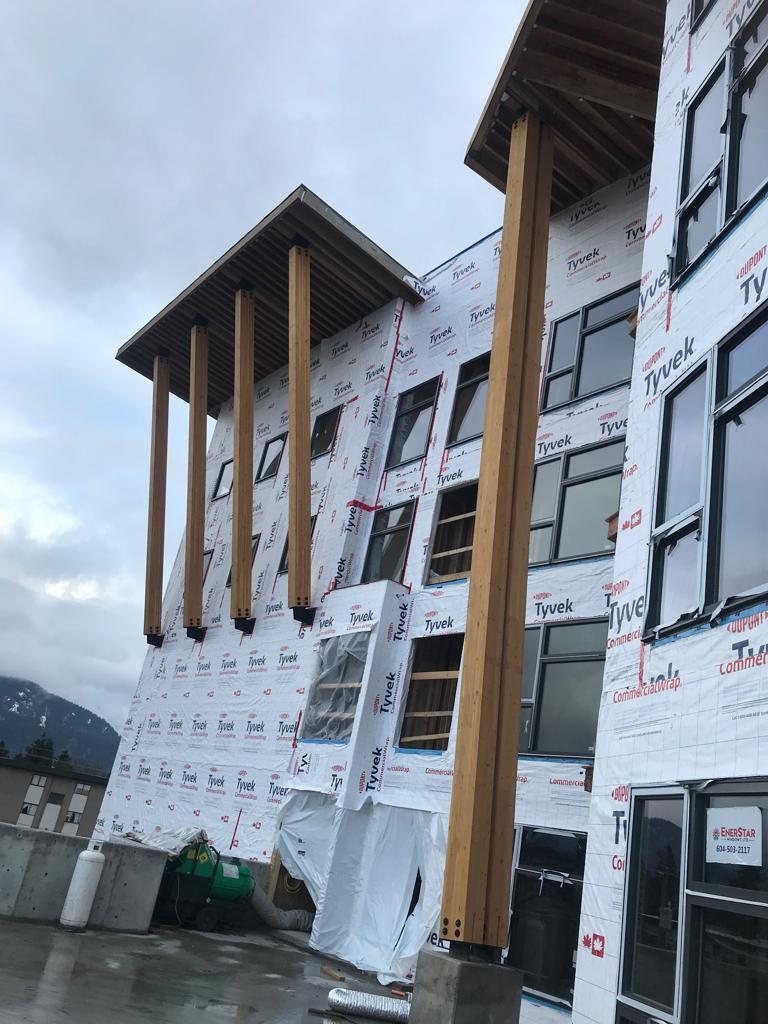 Close view of timber canopy supports and wall framing beside a residential exterior.