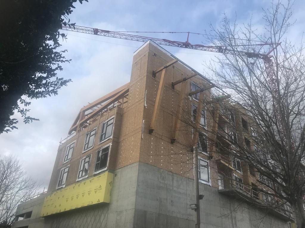 Multi-storey building covered in weather protection beneath an overcast sky.
