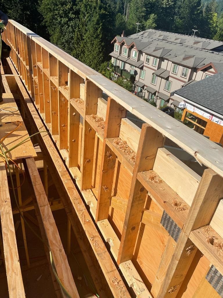 Close view along a timber-framed edge with a temporary guardrail.