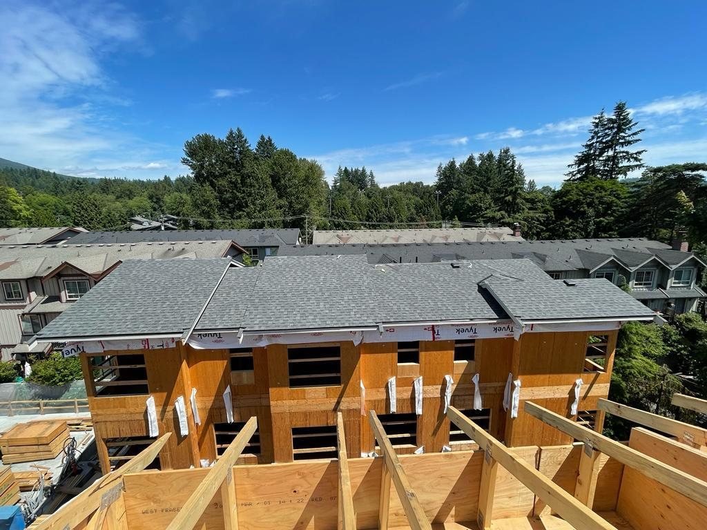 Timber roof framing in the foreground overlooking a row of attached homes.