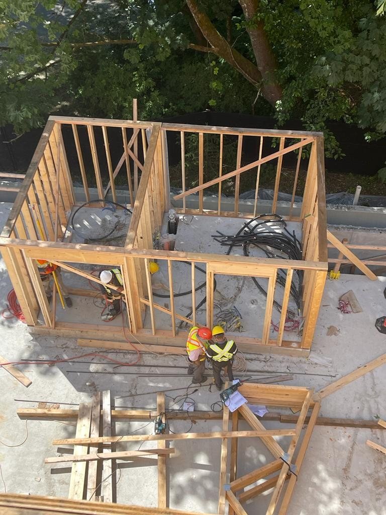 Elevated view of wood roof framing and wall sections during construction.