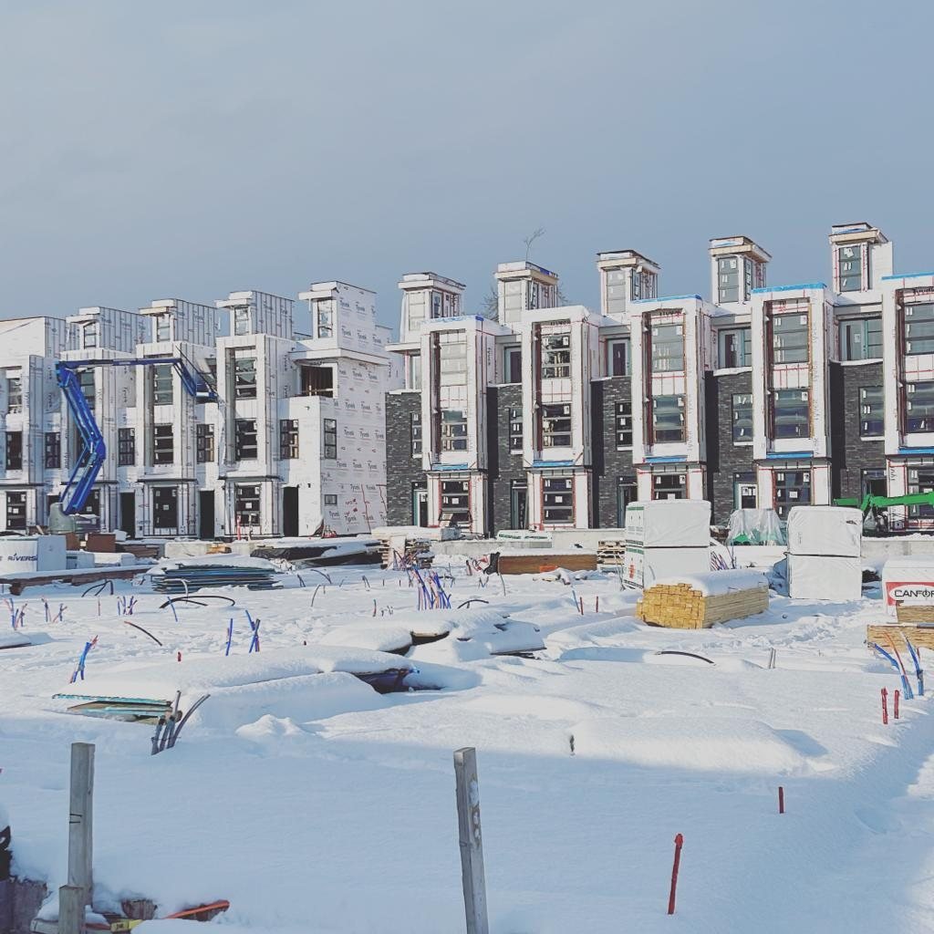 Snow around multi-family building frames and construction materials.
