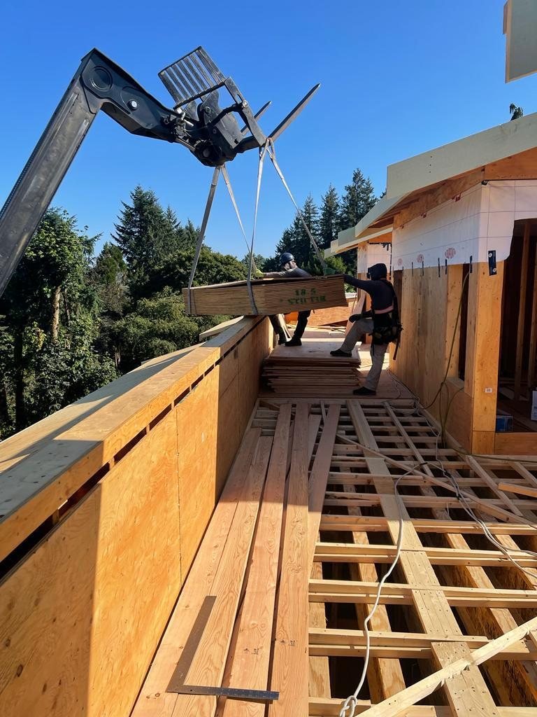 Telehandler boom placing a material package beside wood framing at an upper level.