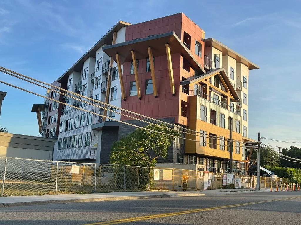 Street-side view of a multi-storey residential building with exposed wall framing and balconies.