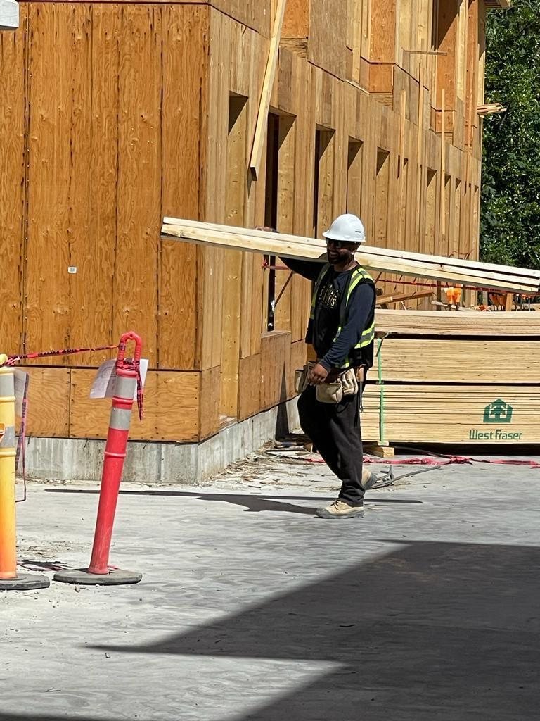 Worker fastening a structural panel to an exterior wood-framed wall.