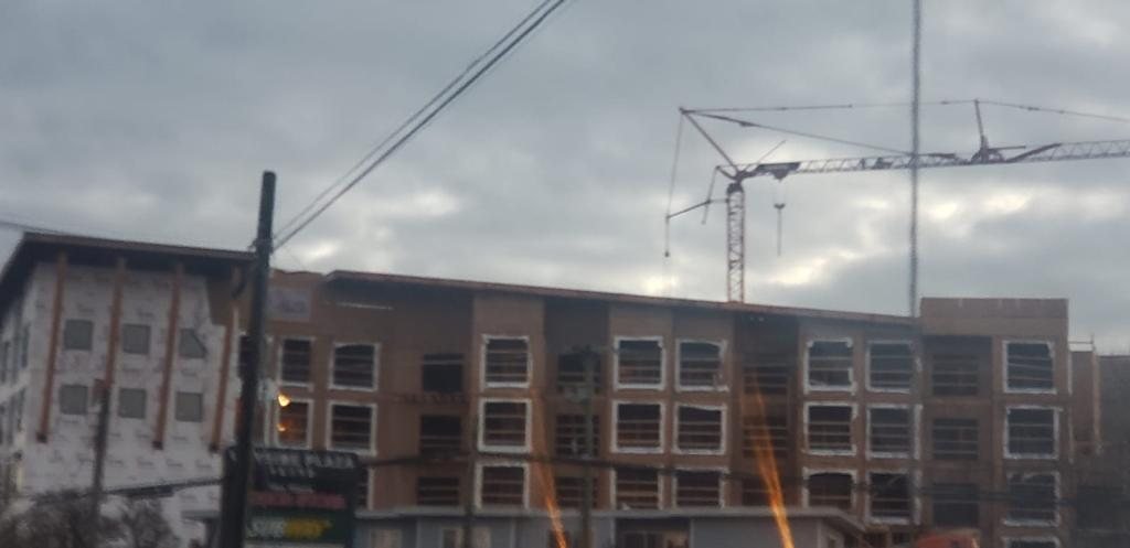 Wood-framed multi-unit building viewed through roadside utility lines.