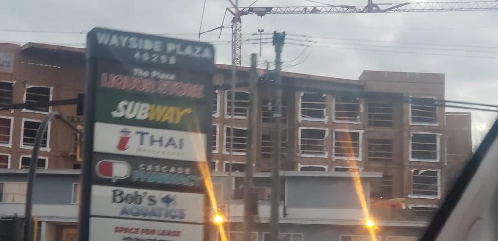 Multi-storey wood framing behind street-side signs for nearby businesses.