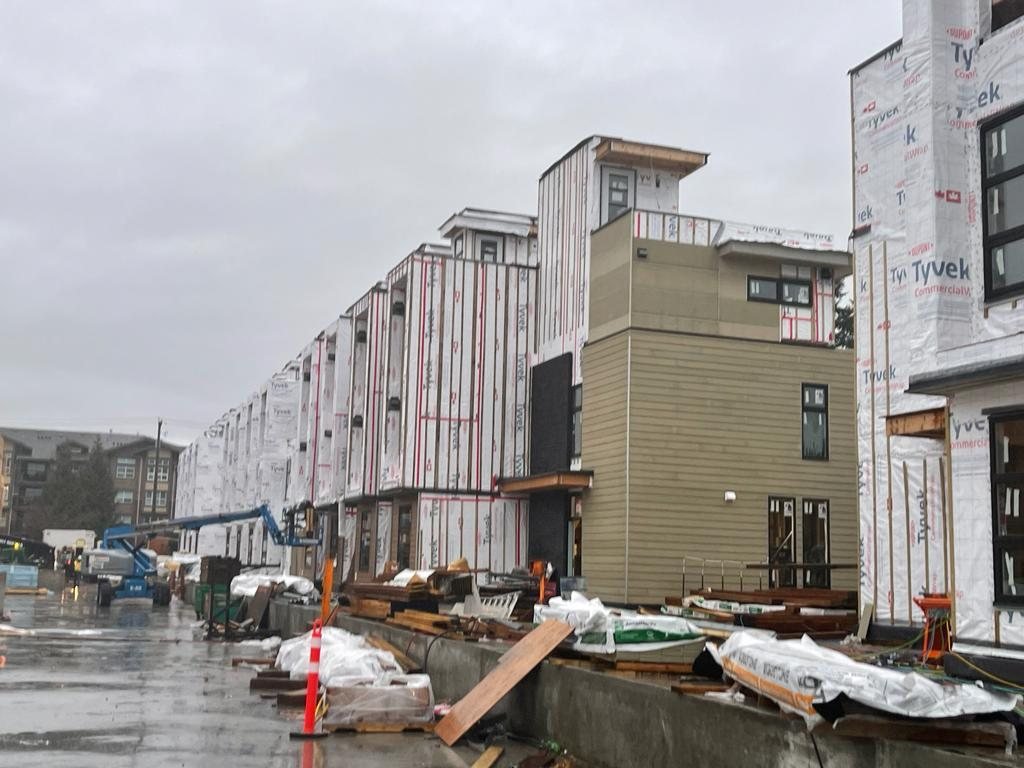 Wrapped multi-storey buildings beside a wet construction access lane.