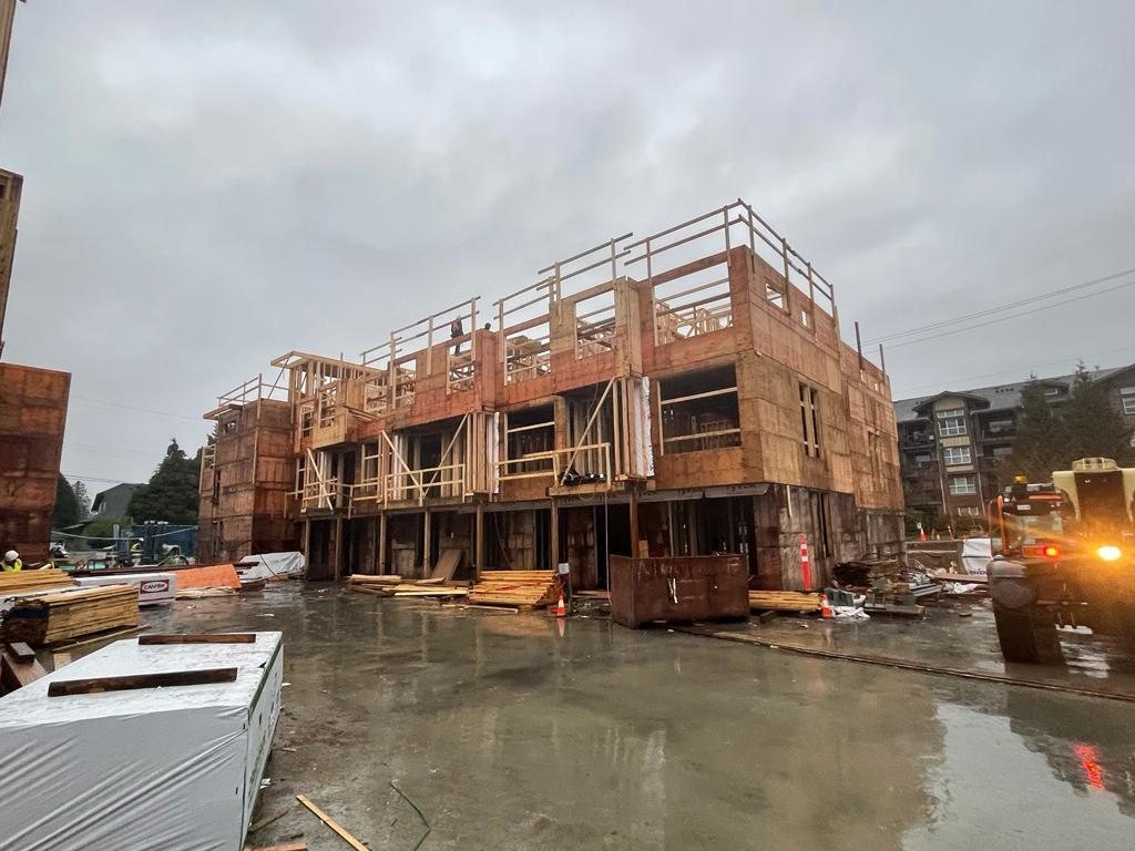 Partially framed multi-storey building on a wet residential construction site.