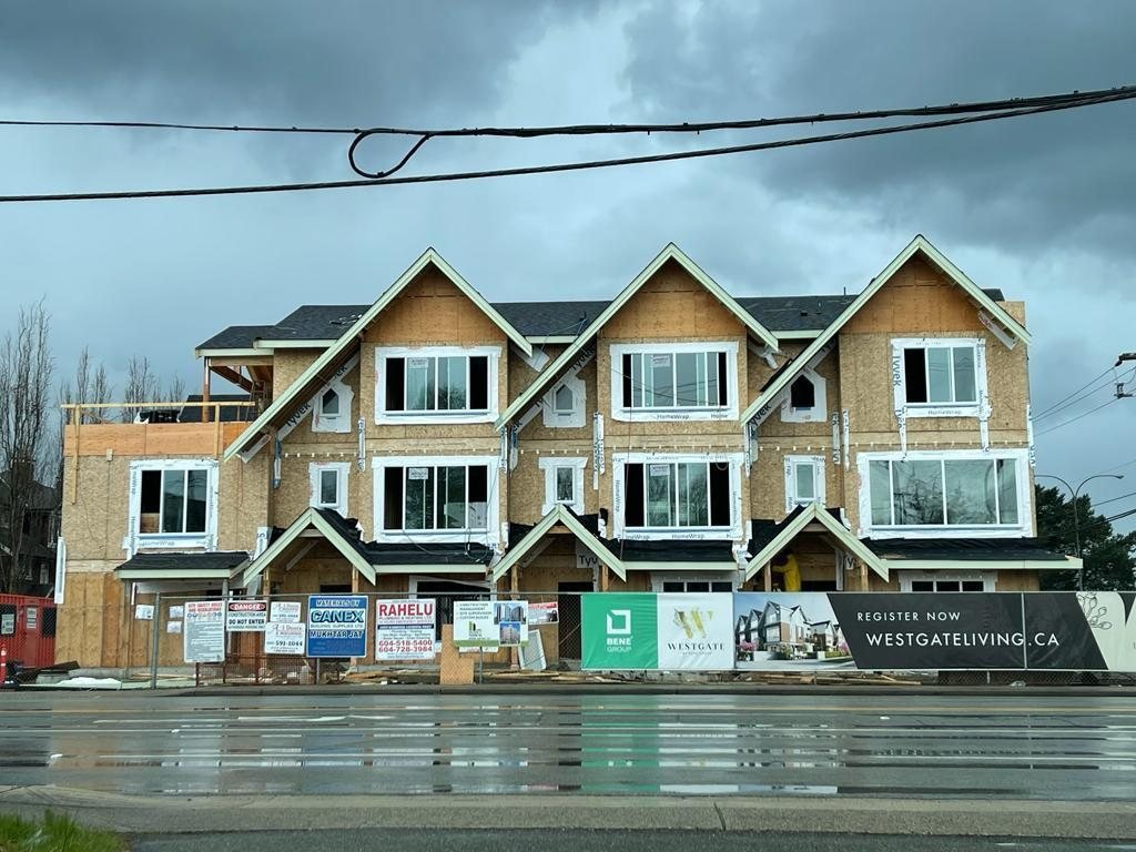 Row of attached homes with exterior finishing under way beside the street.