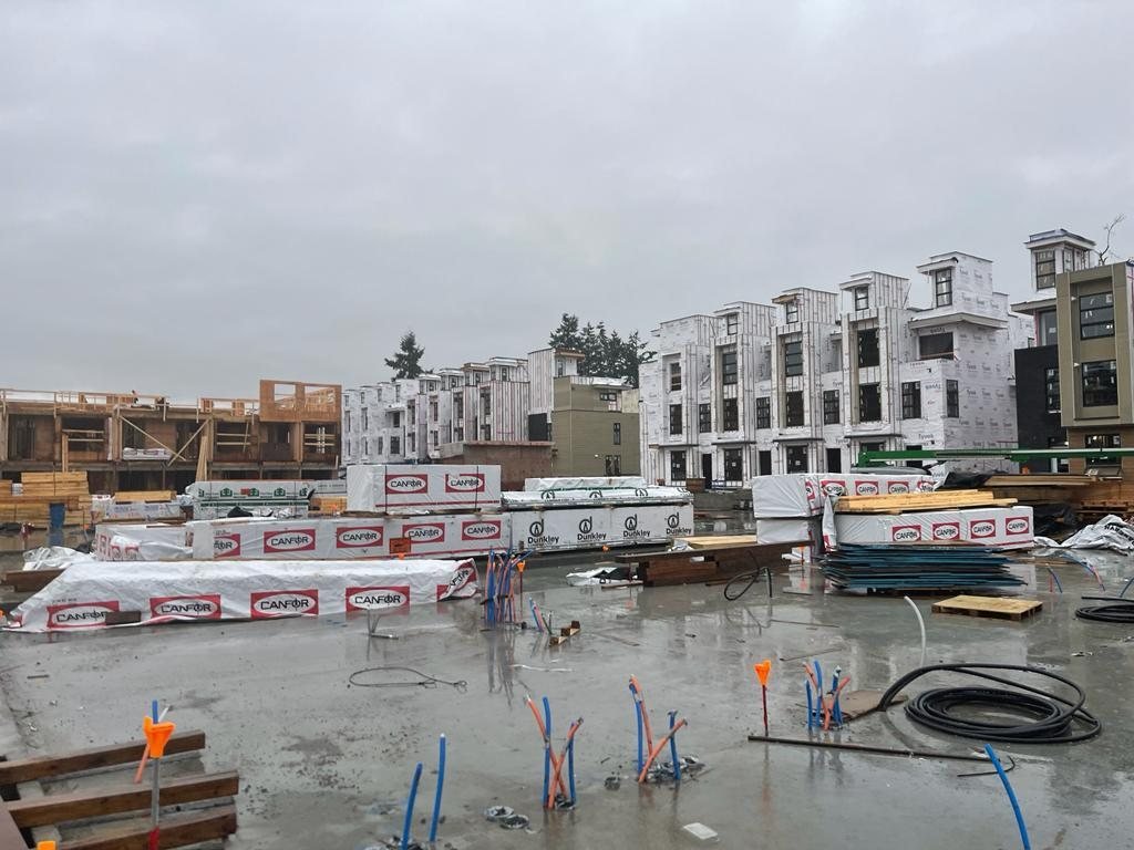 Concrete work area with service conduits and framed multi-unit buildings beyond.
