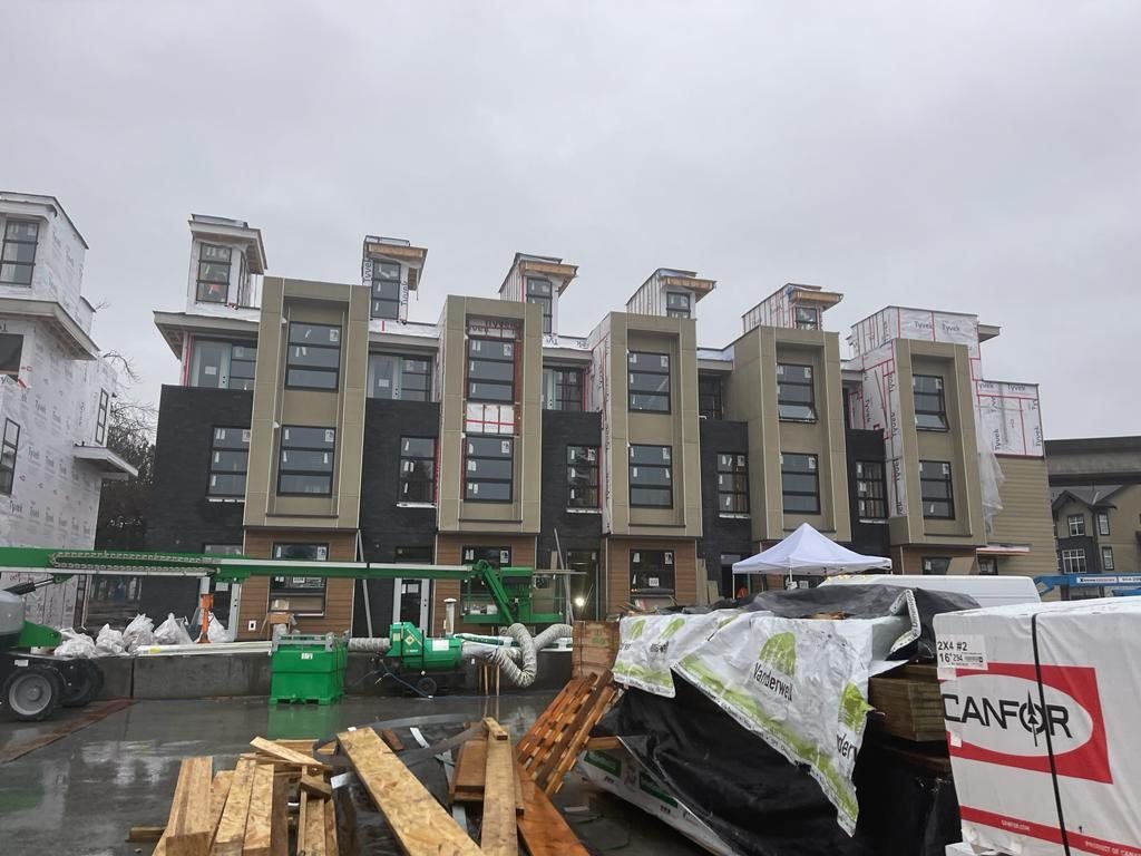 Row of multi-storey attached homes with framing materials near the street.