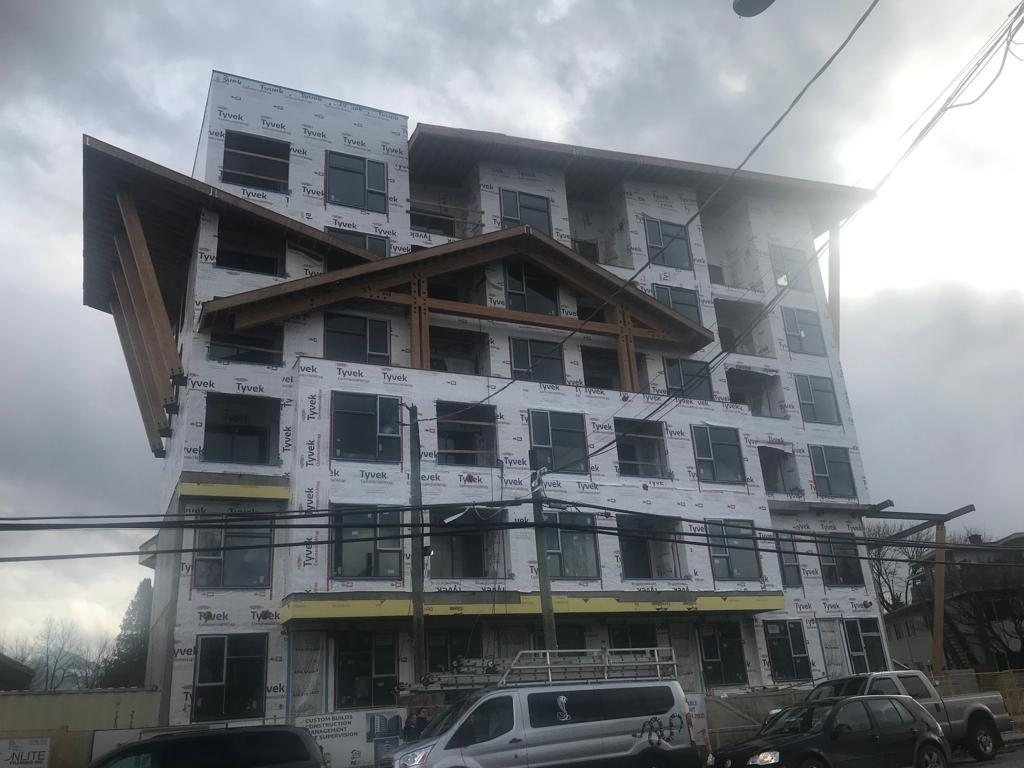 Low-angle view of a multi-storey residential building with balconies and exterior wall panels.