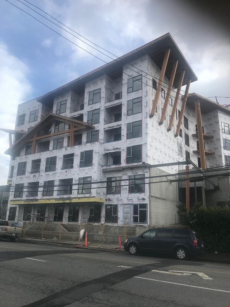 Multi-storey wood-framed building with balconies and weather protection.
