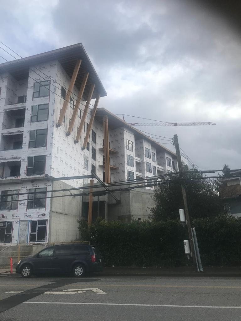 Corner of a multi-storey building with exterior wrap, windows and projecting balconies.