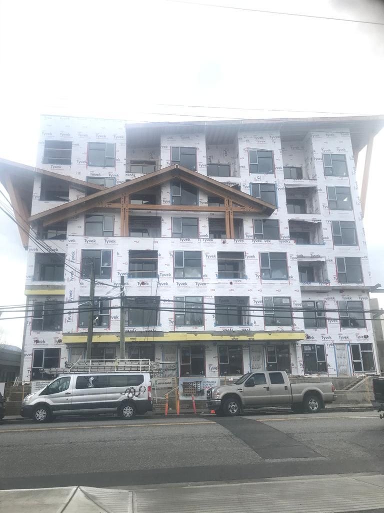 Front-facing view of multi-storey residential construction with balconies and windows.